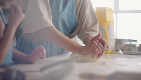 woman-is-teaching-her-preschooler-daughter-to-knead-dough-for-bread-or-pie-closeup-view